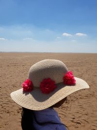 Side view of girl wearing hat while standing at beach during sunny day