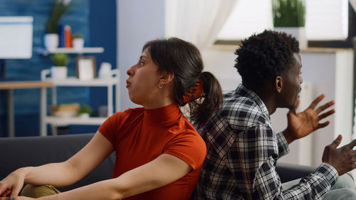 Angry couple sitting on sofa at home