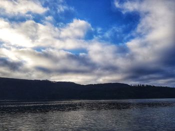 Scenic view of lake and mountains against cloudy sky