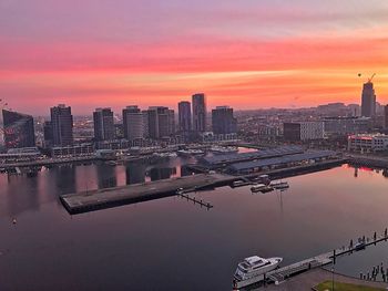 Scenic view of river by buildings against sky during sunset