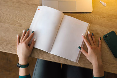 Mockup of an open notebook or book in the hands of a young woman at a desk