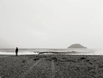 Silhouette man standing at beach against sky