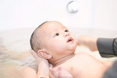 Midsection of mother bathing baby daughter in bathtub