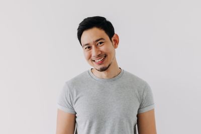 Portrait of young man standing against white background