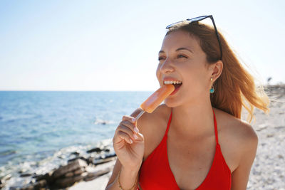 Summer days. beautiful bikini woman biting a fresh popsicle on the beach.