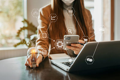 Midsection of woman using laptop on table