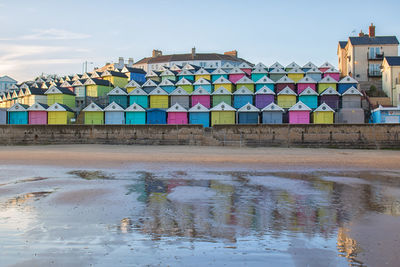 Multi colored houses on beach by building against sky