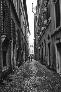 Rear view of people walking on street amidst buildings