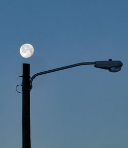 Low angle view of lighting equipment against clear blue sky