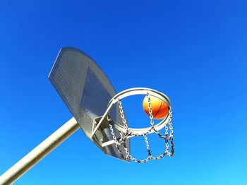 Low angle view of basketball hoop and ball against blue sky