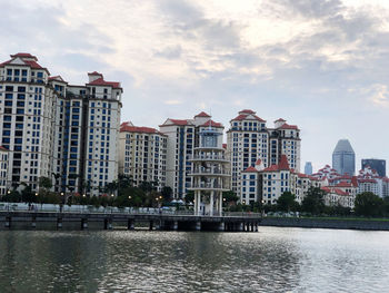 Buildings by river against sky in city