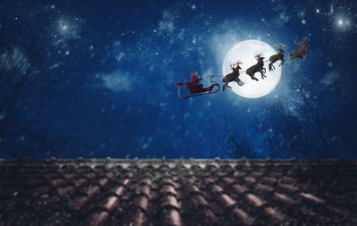 Low angle view of person paragliding on roof against sky at night