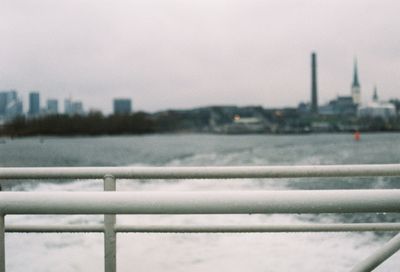 Close-up of railing by river against sky during winter