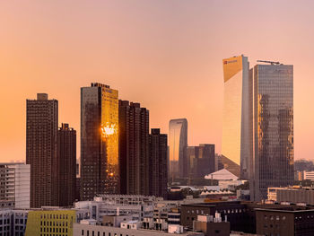 Skyscrapers in city against sky during sunset
