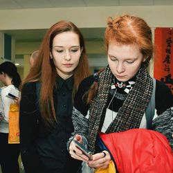 Young woman looking towards friend using smartphone
