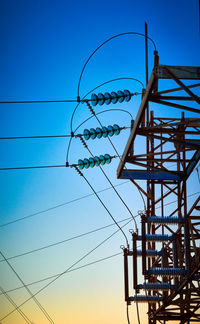 Low angle view of electricity pylon against blue sky