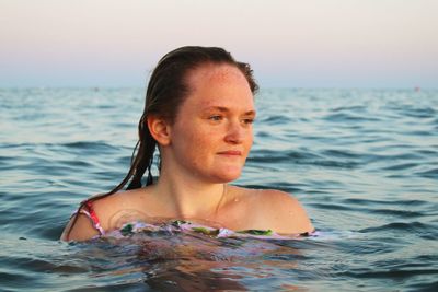 Portrait of shirtless man in sea against sky