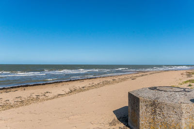 Scenic view of beach against clear blue sky