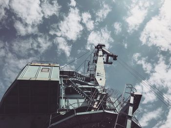 Low angle view of crane at construction site against sky