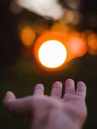 Close-up of hand against illuminated light
