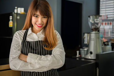 Portrait of confident young female barista standing in cafe