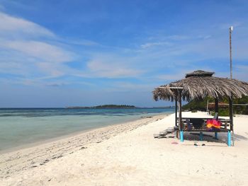 Relaxing hut on beach against sky