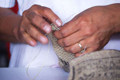 Midsection of person stitching sack