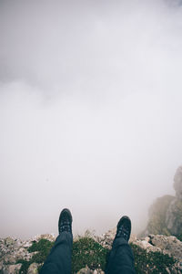 Low section of man lying on mountain peak against fog