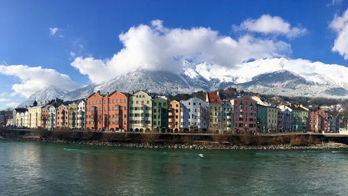 Panoramic shot of buildings by snowcapped mountains against sky