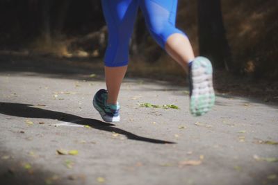 Low section of woman running on footpath