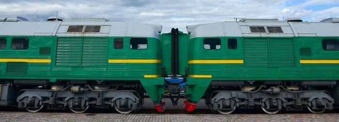 Train at railroad station against cloudy sky