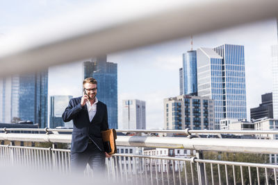 Young businessman walking in the city, talking on the phone