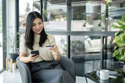 Young woman using mobile phone while sitting in cafe