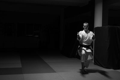 Full length portrait of young man practicing martial arts on floor