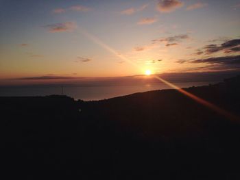 Sun shining through clouds over sea