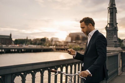 Man standing by railing in city against sky