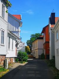 Street amidst houses and buildings against blue sky