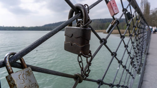 Close-up of padlock on railing by river