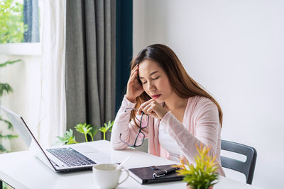 Woman using phone while sitting on table