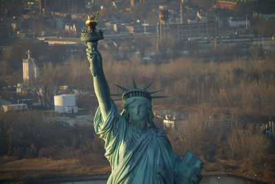 The statue of liberty in front of new jersey industrial suburbs, nyc.