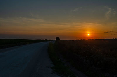 Road amidst plants against sky during sunset