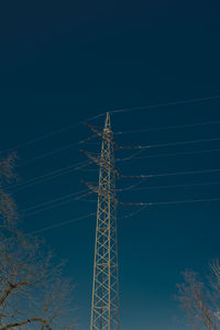 Low angle view of electricity pylon against sky at night