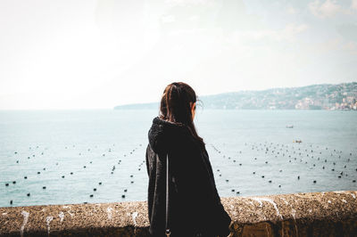 Side view of woman looking at sea while standing on observation point against sky