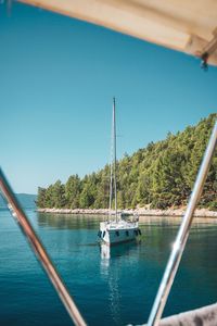 Boats sailing in sea against clear sky