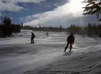 People on snow covered landscape against sky