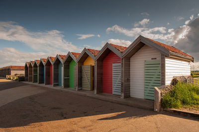 Beach huts by buildings against sky