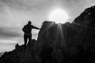 Rear view of woman standing on cliff against sky