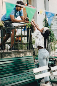 Young man giving food to female friend from balcony during garden party