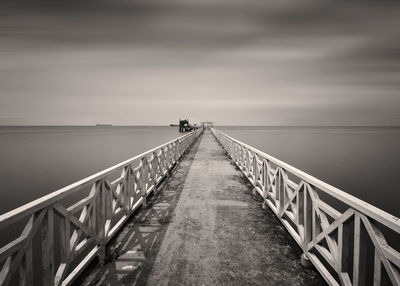 Bridge over sea against cloudy sky