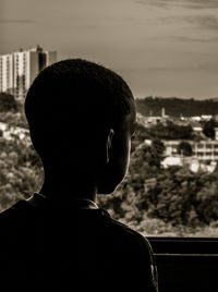 Rear view of boy looking through window